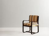 une chaise avec une assise et des accoudoirs rembourrés à rayures, posée sur une surface blanche