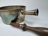 a silver pot with a wooden handle next to a metal bowl