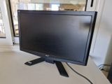 un écran d'ordinateur posé sur un bureau devant une fenêtre
