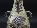 un vase vert orné d'un motif sur fond noir