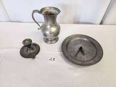 a silver pitcher and a clock sitting on a table