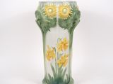 un vase sur lequel sont peintes des fleurs jaunes sur fond blanc