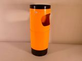 une poubelle orange avec un couvercle noir posée sur une table