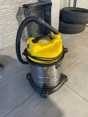un aspirateur jaune posé par terre à côté d'un tas de pneus