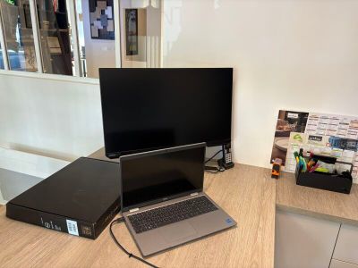 un ordinateur portable posé sur un bureau, à côté d'un écran