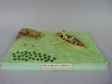 figurine représentant un homme dans un bateau avec un chien et un autre homme dans un bateau sur un lac