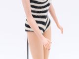 a doll that is standing on a stand with a black and white striped top