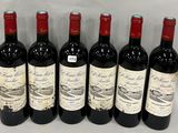 six bottles of red wine lined up in a row on a white surface