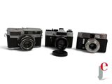three cameras sitting next to each other on a white surface