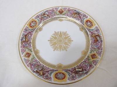 une assiette blanche ornée d'un motif doré et rose