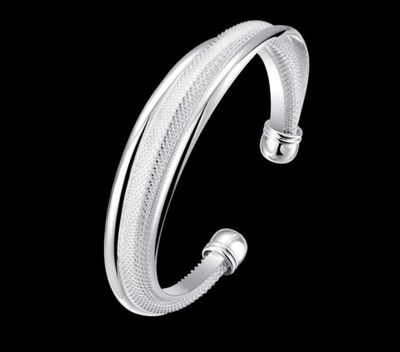 un gros plan d'un bracelet manchette en argent sur fond noir