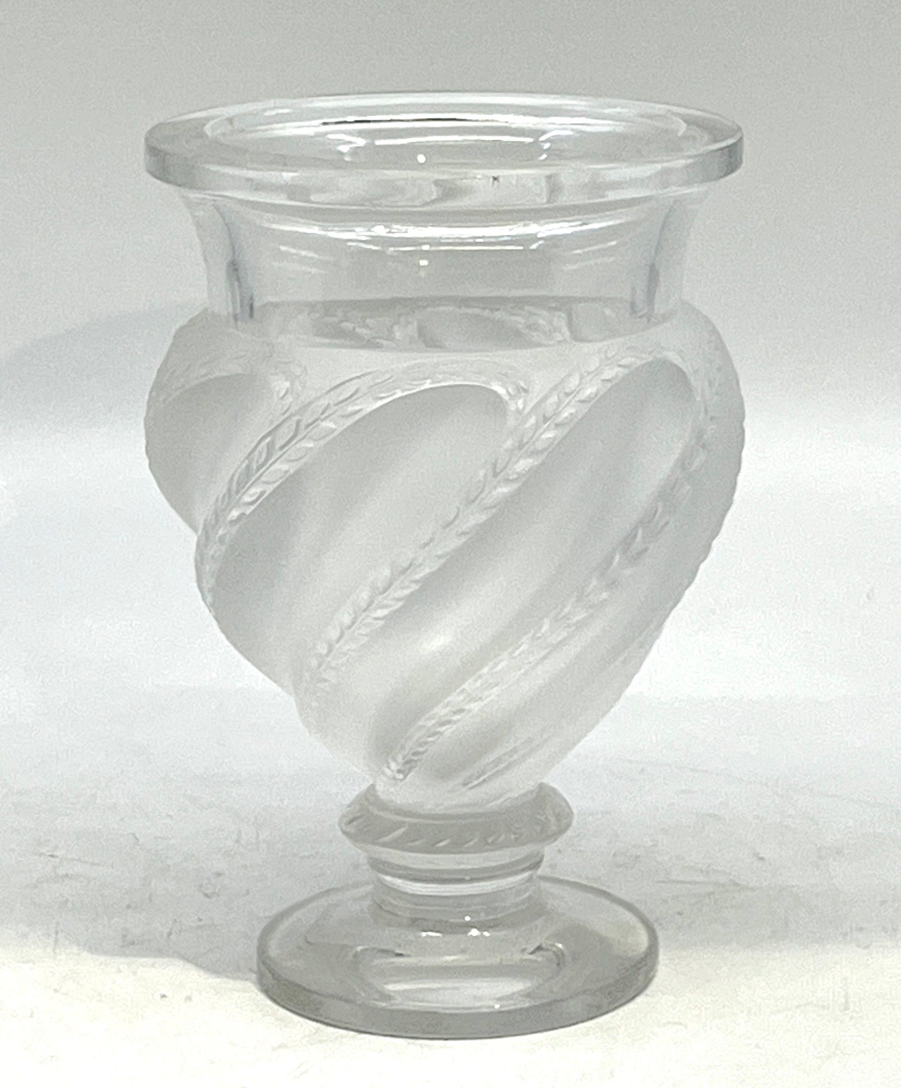 LALIQUE France, modèle "Ermenonville". Vase en verre pressé-moulé à décor torsadé de frise de feuille. Signature à la...