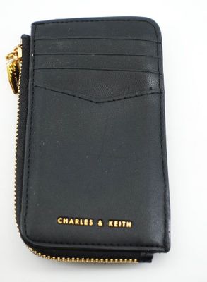 portefeuille en cuir noir avec fermeture éclair dorée et chaîne sur fond blanc
