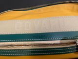 yellow, green and white striped bag with zippers on top of it
