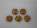 quatre pièces d'or sont disposées en ligne sur une surface blanche