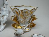 a white vase with gold trim and a gold and white cup and saucer on a white table