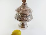 a silver container with a lemon next to it on a white surface