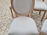 four white chairs sitting on top of a brick floor next to each other