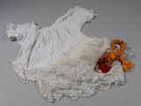 un ours en peluche et une robe blanche posés sur une table