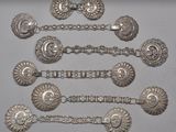 six cuillères en argent et une paire de boucles d'oreilles posées sur une table