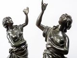 pair of bronze statues of a woman and a man reaching for something