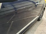 a black car parked in a parking lot next to other cars