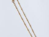 un collier en or avec une longue chaîne sur fond blanc