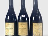 trois bouteilles de vin sont alignées sur une surface blanche