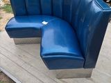 a blue bench with a curved seat on a wooden platform