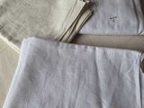trois serviettes en lin blanc posées sur une table, à côté d'une paire de ciseaux