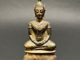 a bronze statue of a seated buddha on a black surface