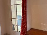 a dresser in the corner of a room with a red curtain