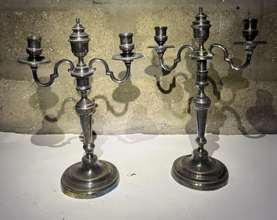 deux chandeliers en argent posés sur une table près d'un mur