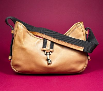 a close up of a gold purse with a black strap