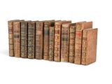 several old books are lined up in a row on a white surface