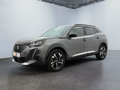 Une voiture grise est garée dans une grande pièce au sol noir.