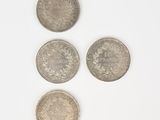 three silver coins sitting on top of each other on a white surface
