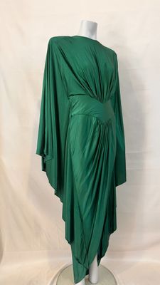 a green draped dress on a mannequin base with a white background