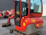 the back end of a red mini excavator parked in a parking lot