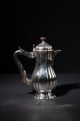 an antique silver coffee pot on a black surface