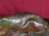 sculpture en bronze représentant un cerf couché sur un fond rouge