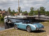 a blue car parked next to a boat on the water