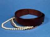 leather belt with pearls and a chain on a blue background