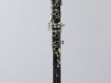 a close up of a black and silver clarinet on a clear stand