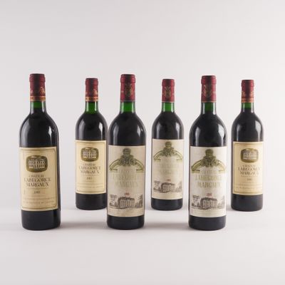 six bouteilles de vin sont alignées sur une surface blanche