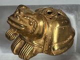 une figurine en or représentant un poisson, exposée dans une vitrine
