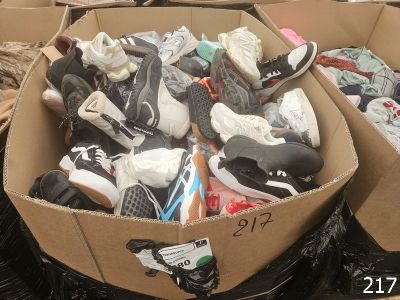 many pairs of shoes in a cardboard box on the ground
