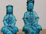 two blue statues of buddhas sitting on top of a wooden table