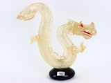une sculpture en verre représentant un dragon, posée sur un socle noir