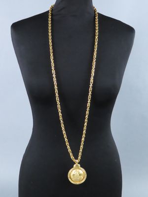 un torse de mannequin sur lequel sont posés une chaîne en or et une pièce de monnaie
